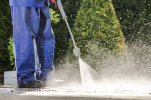 Caucasian Men Washing House Driveway Using Pressure Washer. Cleaning Technologies.